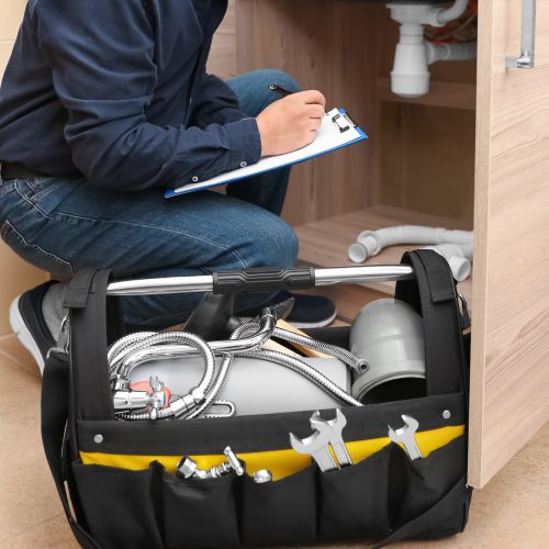 a plumbing technician inspects a drainage system under a bathroom sink